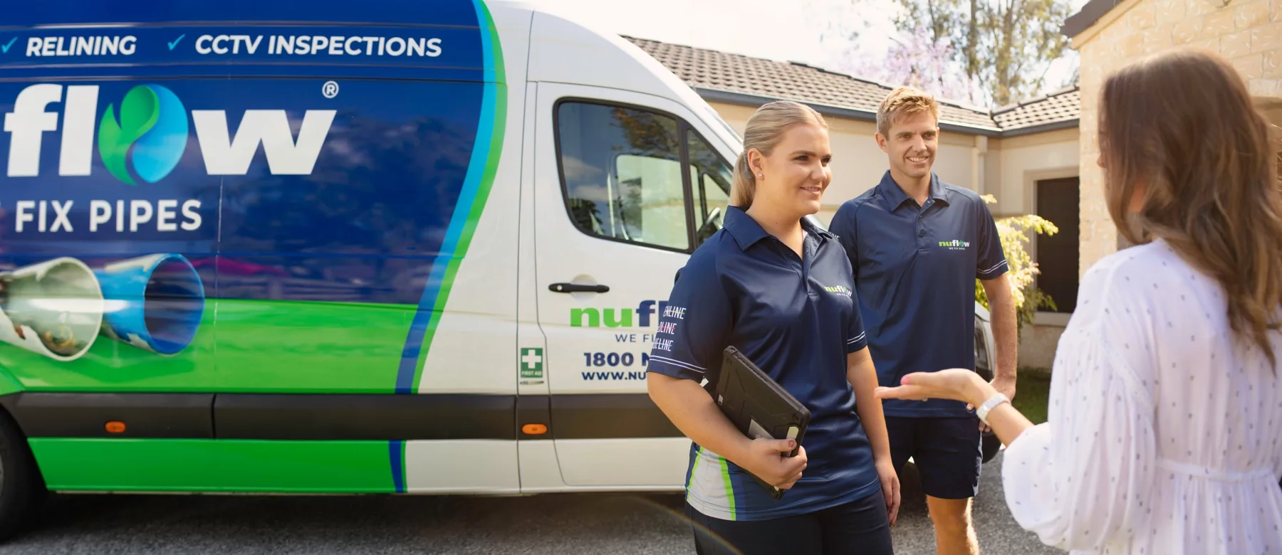 Nuflow technicians speaking with a homeowner beside a branded service van