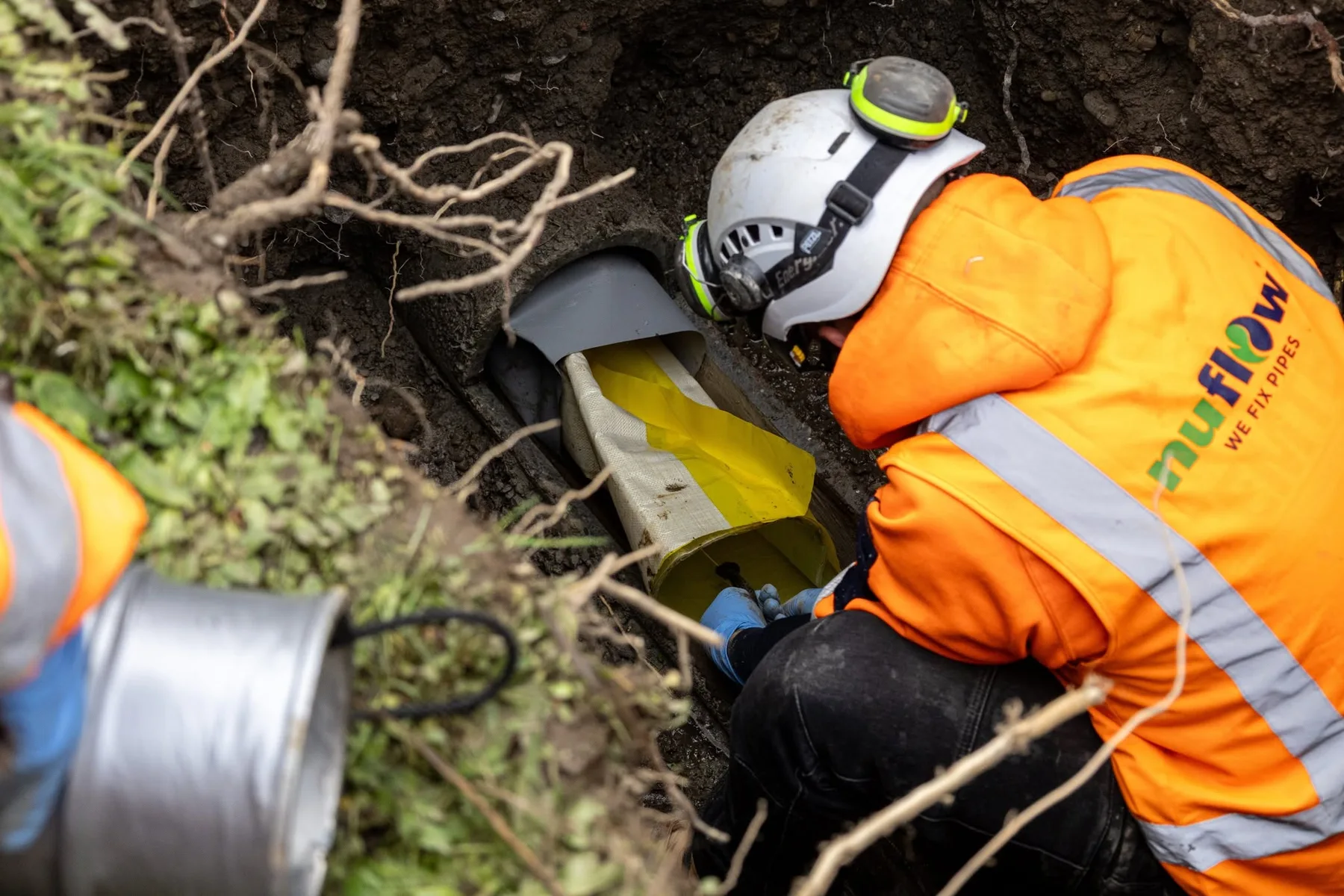 Nuflow technician inserting a liner into an accessible pipe opening